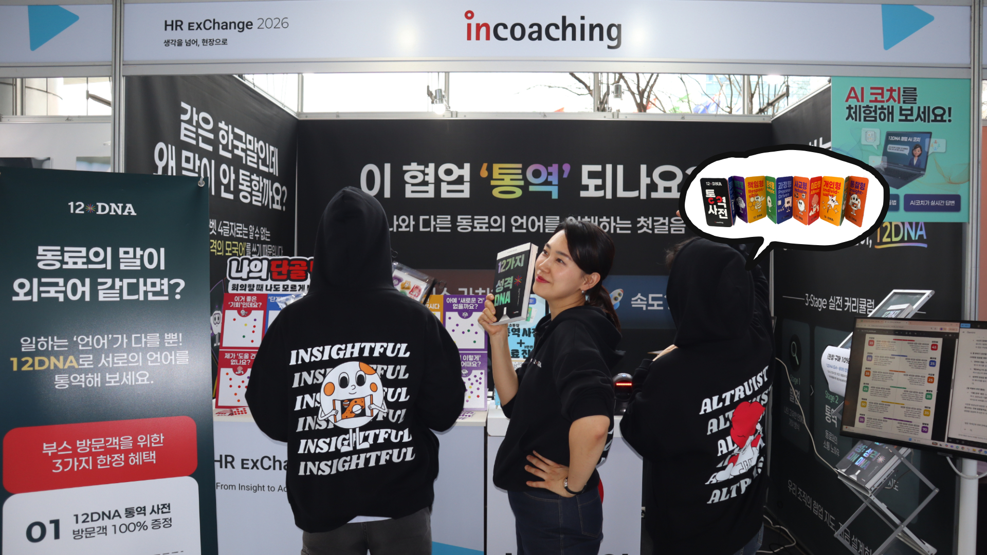 12DNA 협업 통역안내소 부스에서 김재은 대표가 도서와 조기 품절된 12DNA 통역 사전을 소개하고 있으며, 우측에 AI 코치 솔루션 체험존이 마련되어 있는 모습.